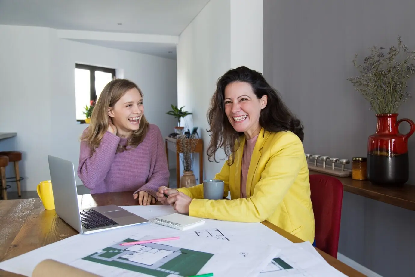 Architektinnen arbeiten mit Zeichnungen und lachen.