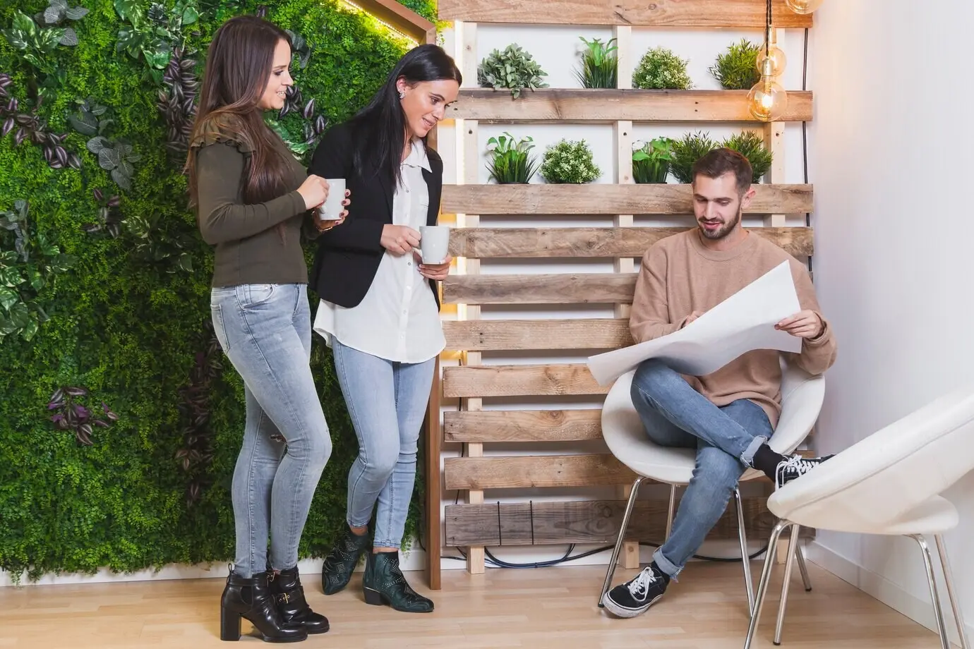 Frauen ruhen sich aus, während ein Mann eine Blaupause liest.